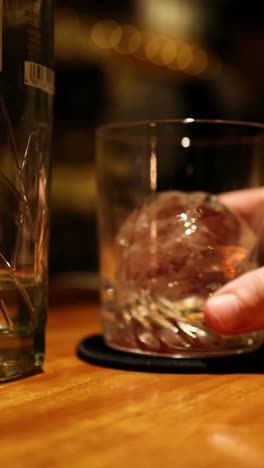 hand swirling ice in a glass tumbler