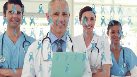 animación de cintas azules de cáncer sobre un equipo diverso de doctores femeninos y masculinos sonrientes