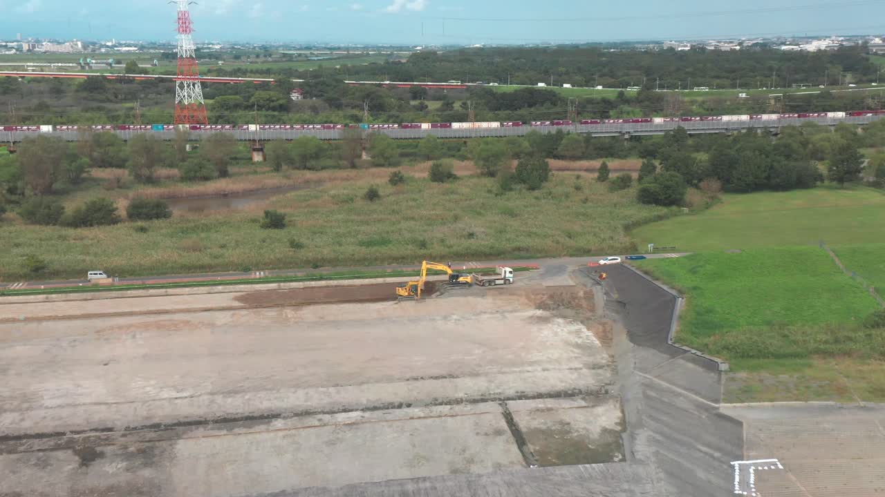 camión junto a las dos excavadoras que cavan en el suelo con un tren de carga que pasa al fondo durante el día en saitama, japón