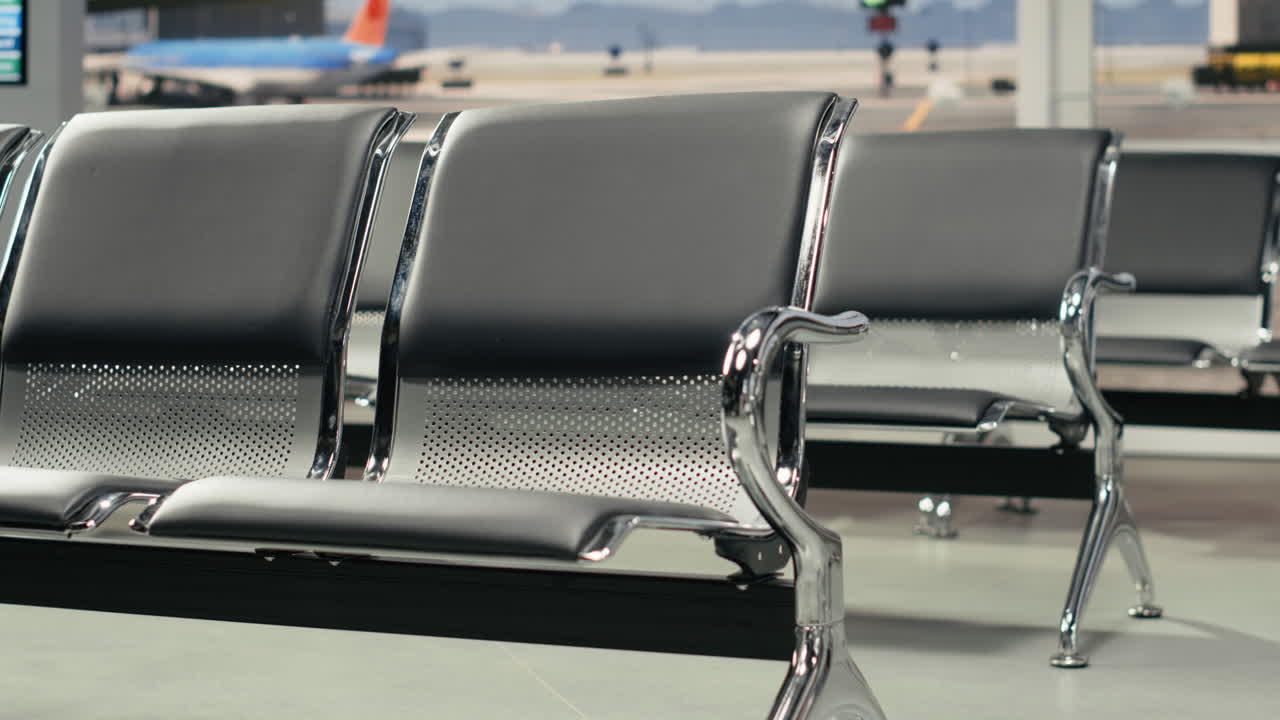 Primer plano de bancos en un pasillo de aeropuerto vacío tras un horario de vuelos retrasado