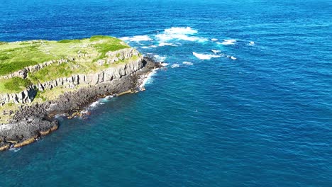 waves crash against hexagonal volcanic rock formations