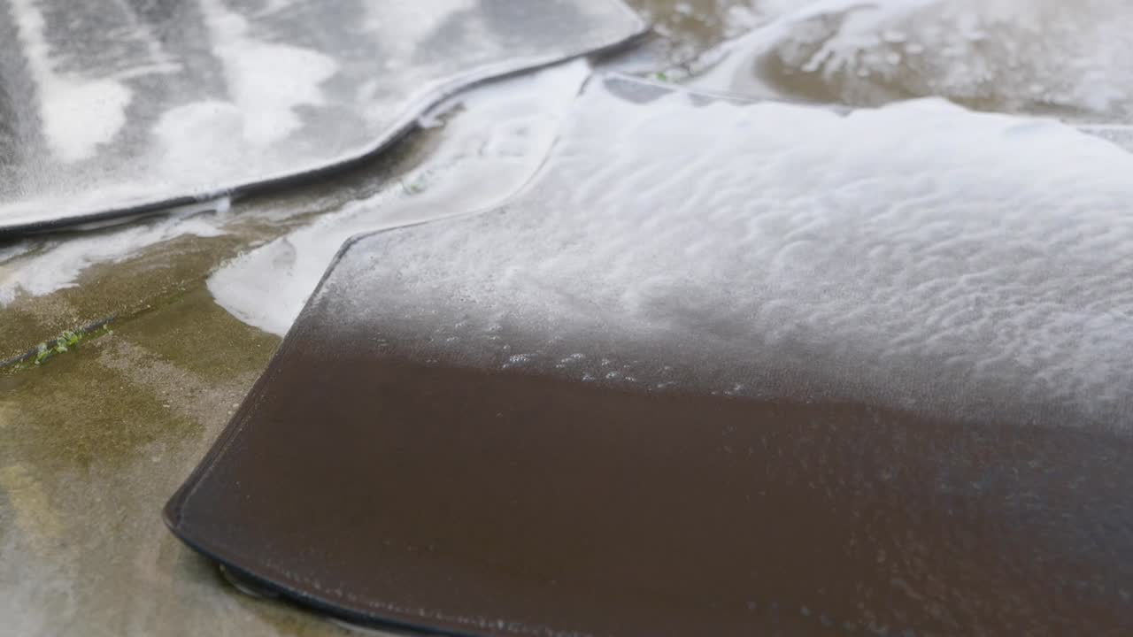 Rinsing small car foot with pressure washer and blue jet wash nozzle - extreme close up - tight shot
