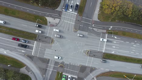 calm suburban road intersection with cars driving straight forward in both directions, top down