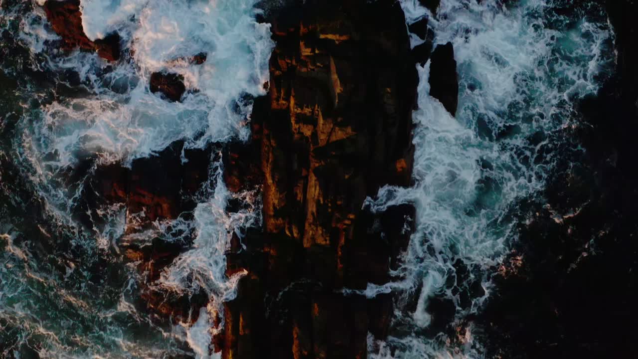 Aerial view ocean crashing on the rocks in