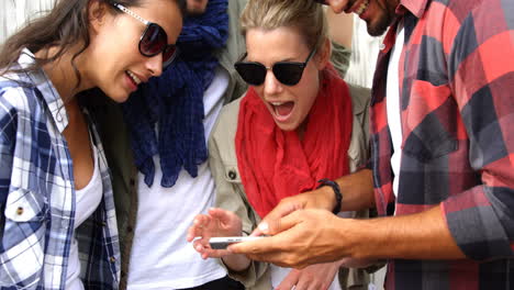 casual friends wearing sunglasses and using smartphone