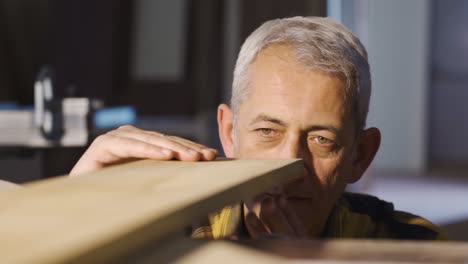 carpenter man examines and touches wood in a carpentry workshop.