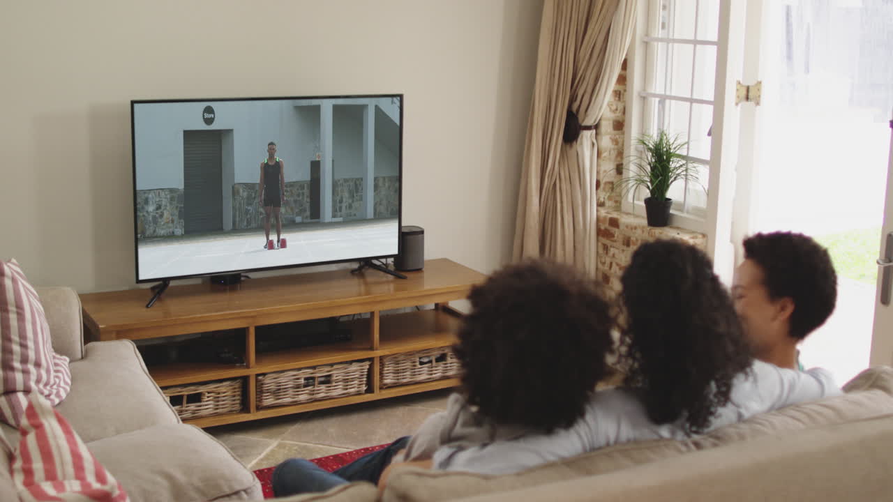 Famiglia felice seduta a casa insieme che guarda un evento di atletica in TV