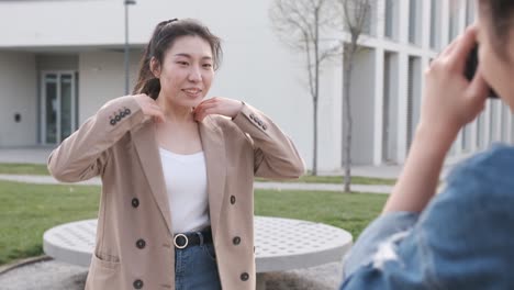 Young asian woman posing to the camera while the photographer girl taking a photo to her.