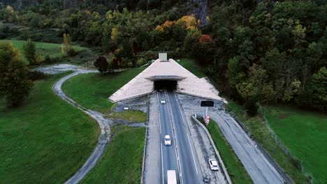 beautiful aerial view over highway roads going into a tunnel in france. only grass fields and trees around the roads. cars and trucks driving on the roads.