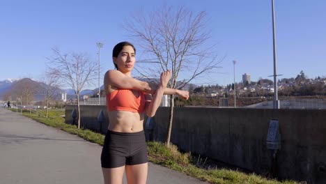 Mujer-Joven-Estirando-Los-Brazos-Y-Sacudiendo-Los-Músculos-Antes-De-Hacer-Ejercicio-Al-Aire-Libre