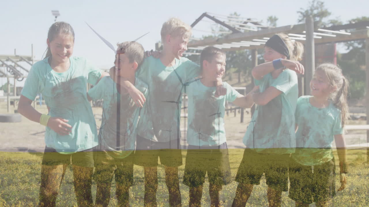 In field, children in muddy clothes smiling near wind turbines, enjoying animation