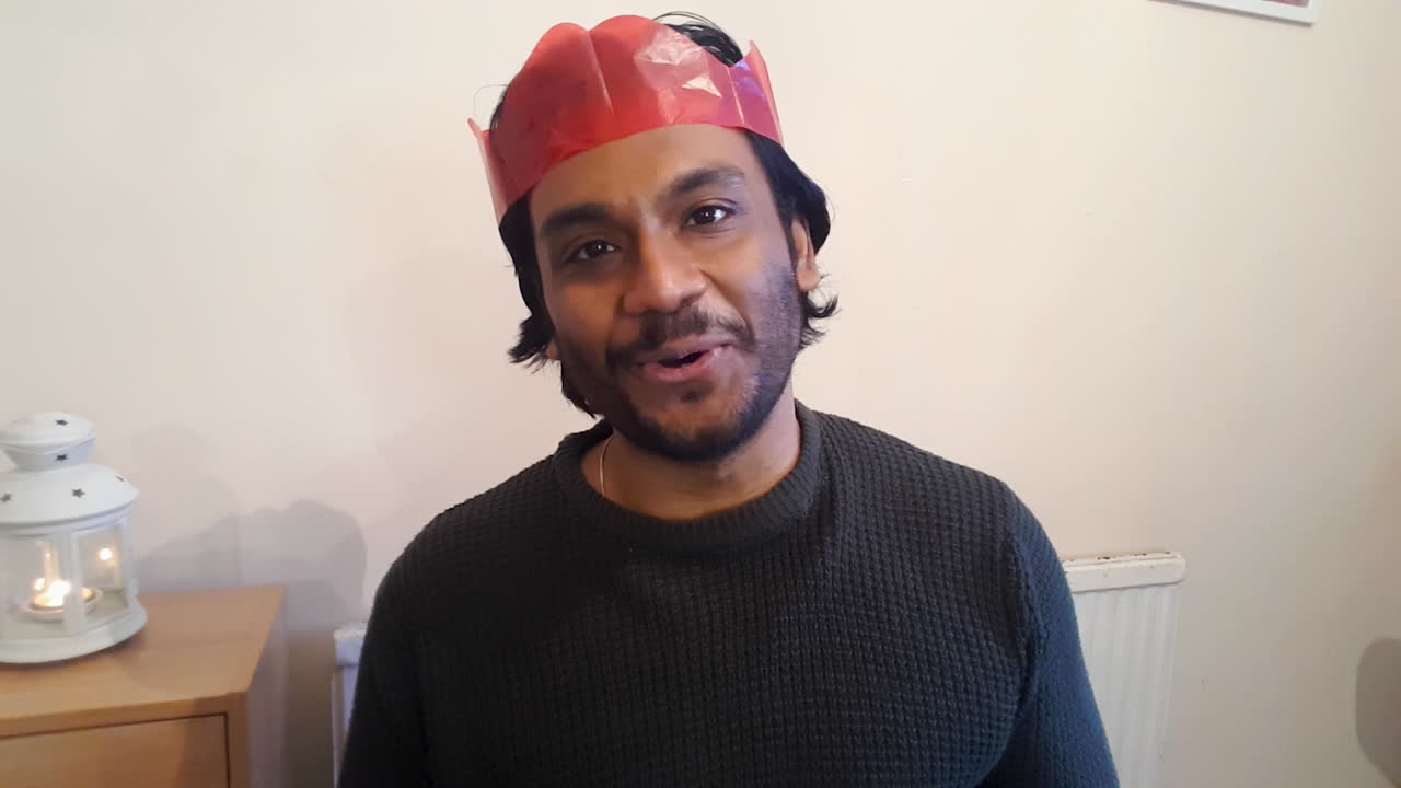 joven en videollamada navideña hablando y levantando vidrios a la cámara