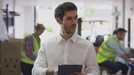 male manager in busy logistics distribution warehouse using digital tablet