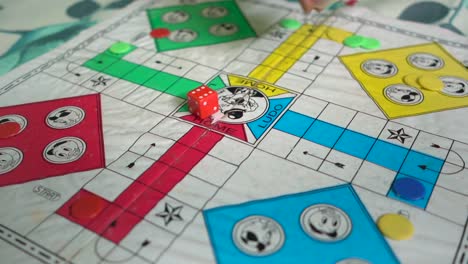 hand of old woman rolls dice of ludo in the board game at home during quarantine, shallow focus and slow motion shot