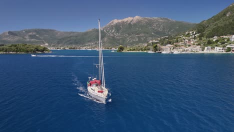 aerial: large sailing yacht motors out of nydri harbour in greece