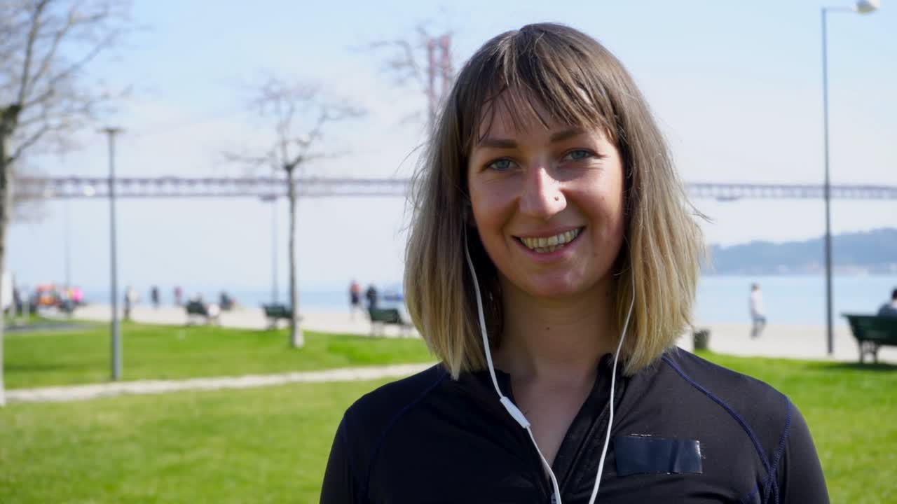 Ritratto di giovane donna felice in abbigliamento sportivo che guarda la telecamera all'aperto