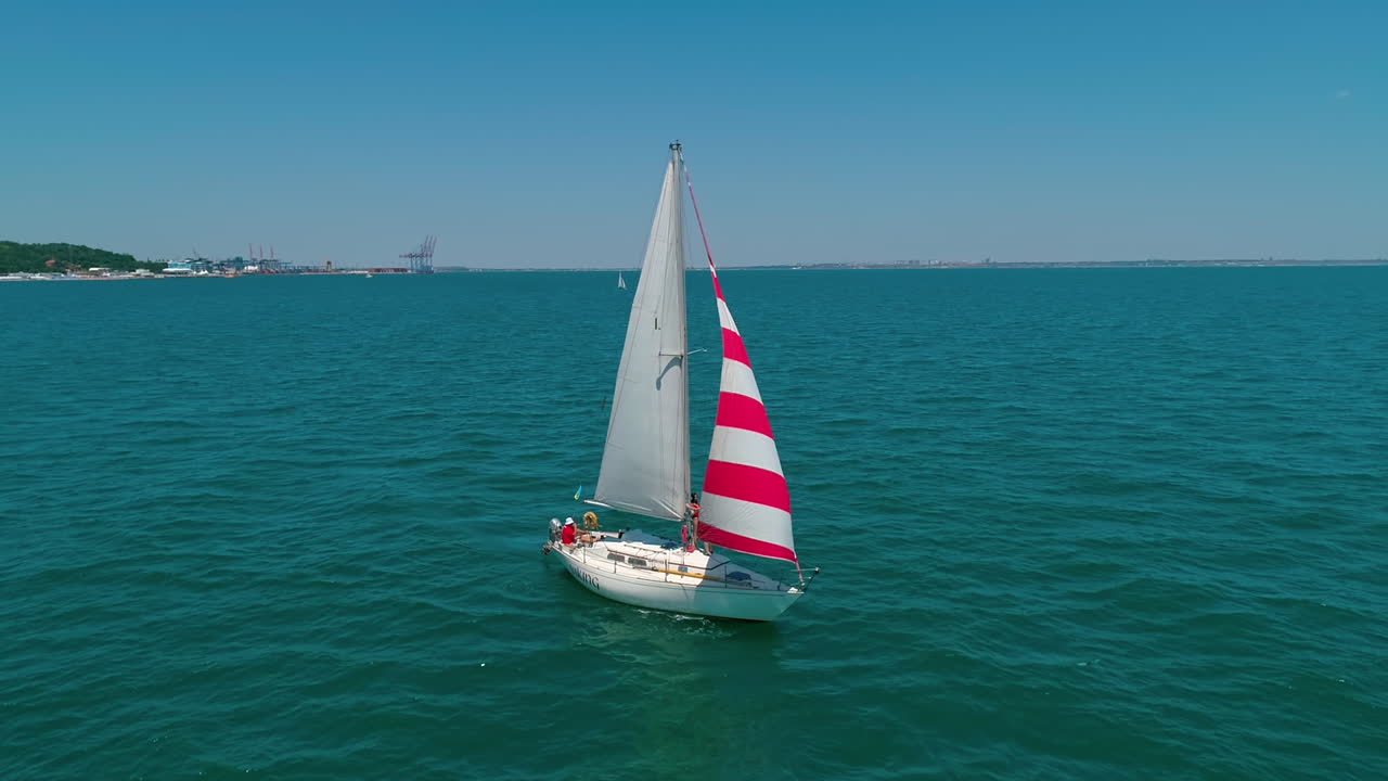 Beautiful boat with sails on water. Yacht sailing in sea on the coastline background. Sailboat floating.