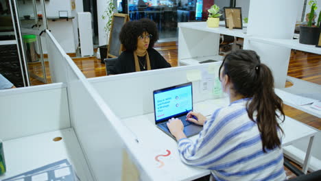 female coworkers sitting at office cubicles and chatting