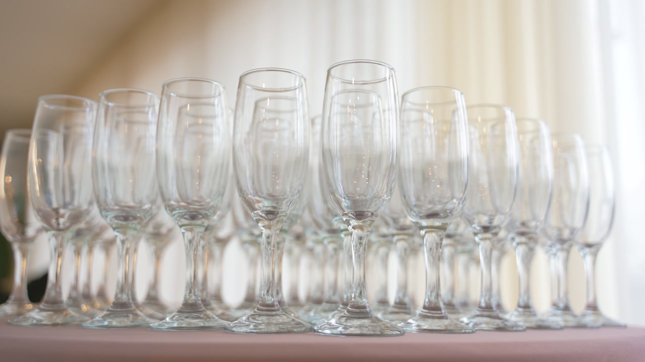 Close-up shot of multiple empty champagne glasses arranged in neat rows, softly illuminated by warm light