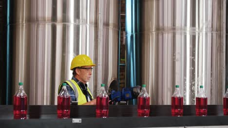 Worker-using-digital-tablet-in-bottle-factory