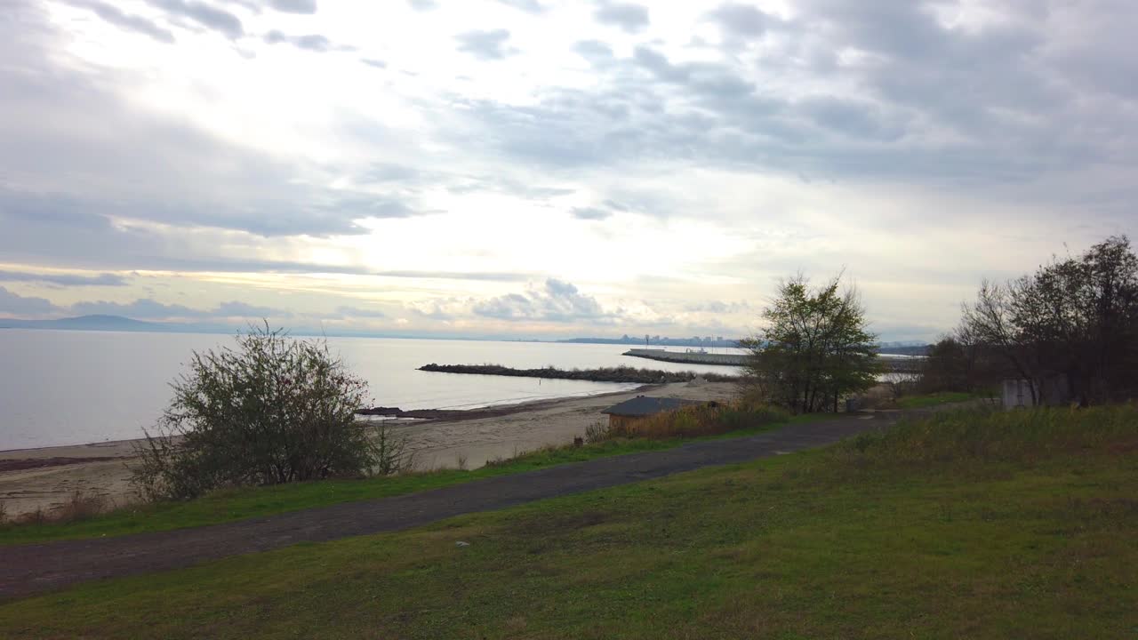 Morning panorama to the Black sea with rock piers, empty beach and  beautiful clouds. View from green meadow to the beach in Sarafovo bay, Bulgaria. Pan left.