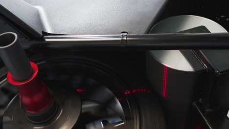 car technician using auto wheel balancer machine to repair wheel, closeup