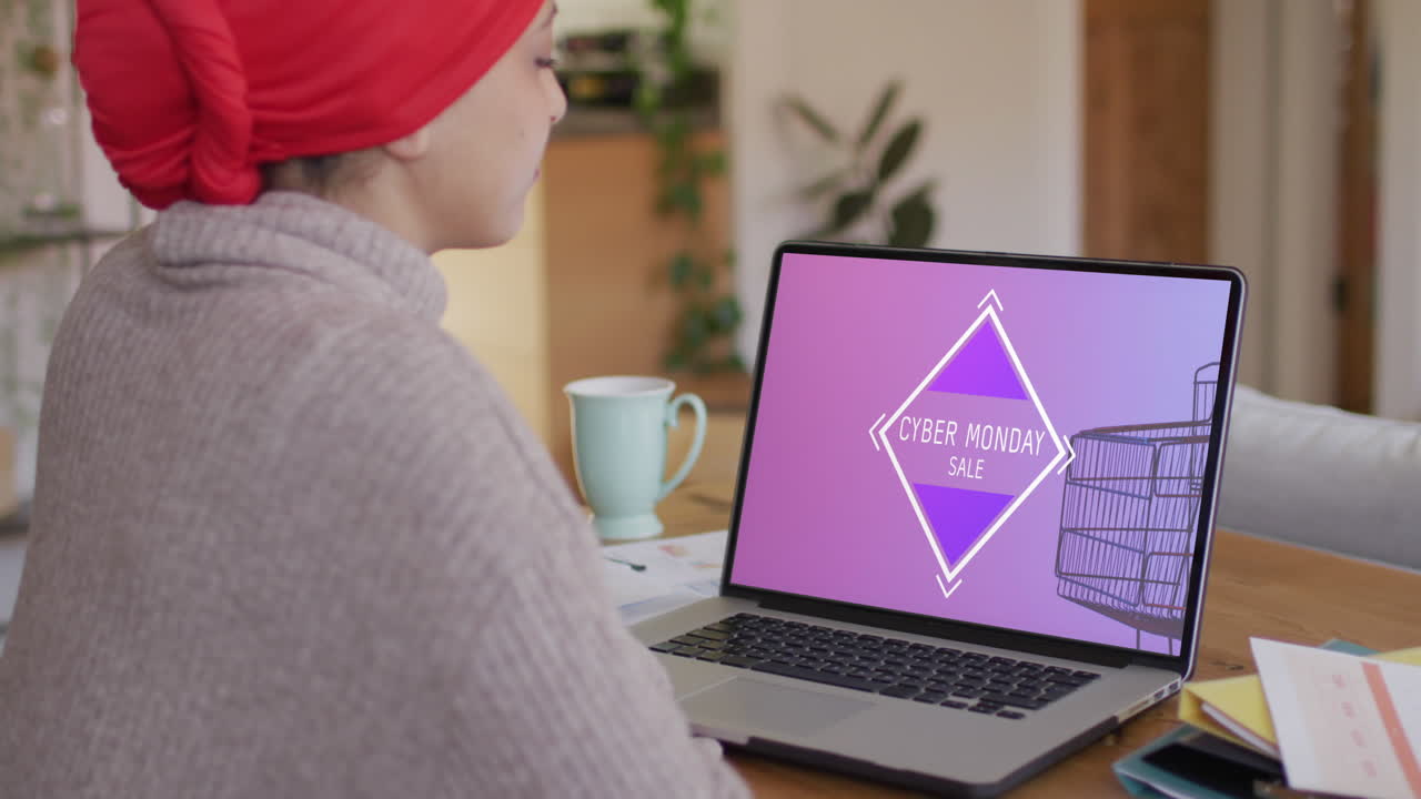 mujer biracial en la mesa usando portátil, compras en línea en el lunes cibernético, cámara lenta