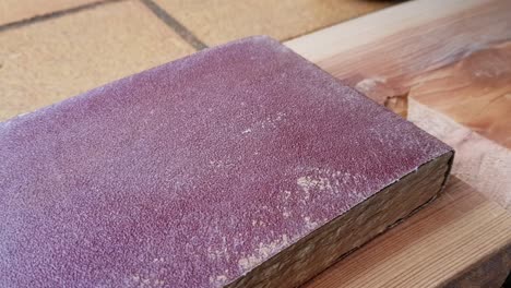 paneo de cerca a la derecha en papel de lija rojo sentado encima de un tablón de madera
