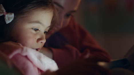 mother and child using tablet computer mom teaching little girl playing games on touchscreen technology having fun before bedtime