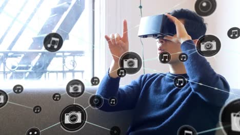 Animation-of-network-of-connections-with-icons-over-man-wearing-vr-headset