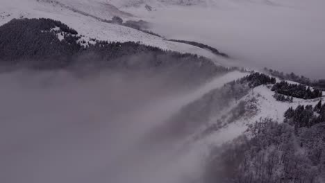 drone flying over mountain peak covered with snow and fog