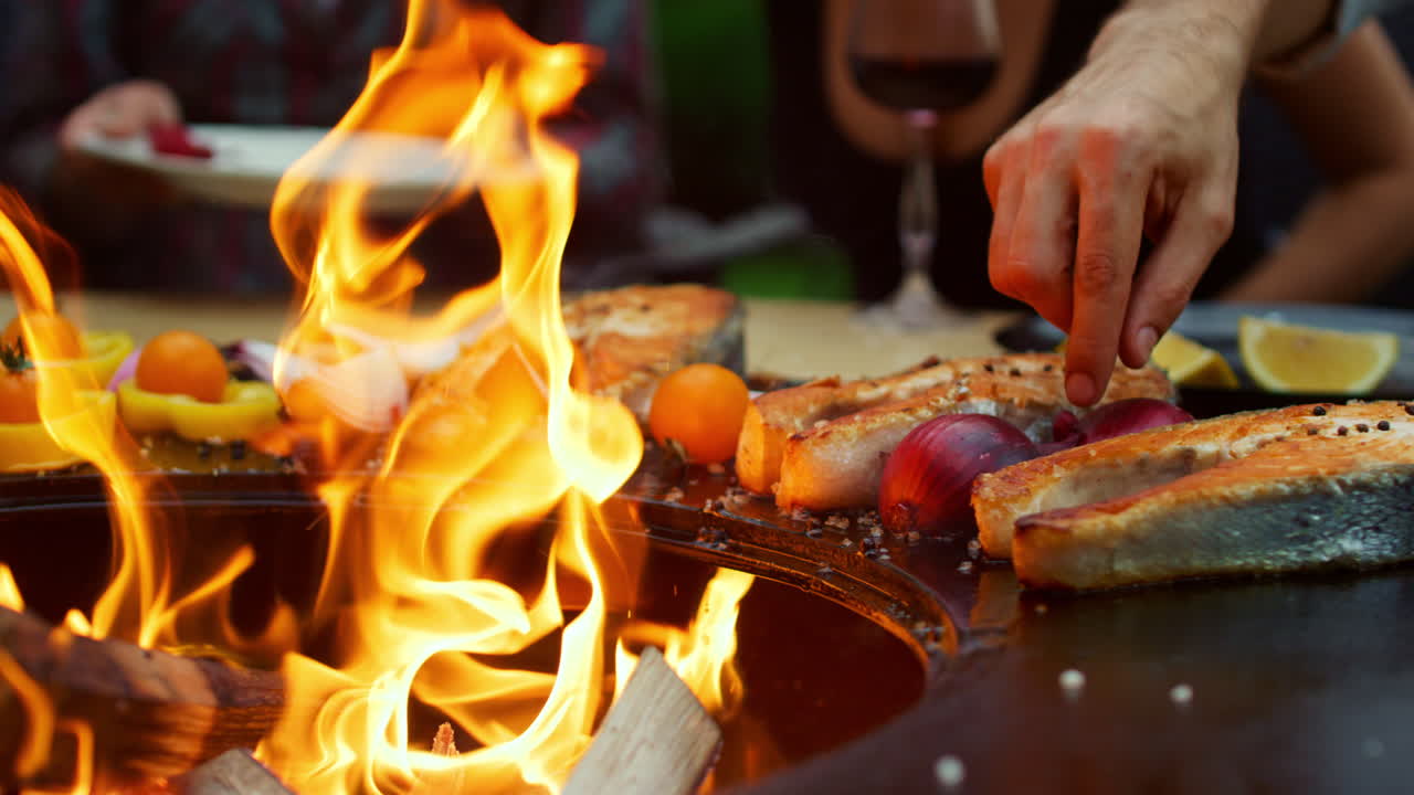 Uomo irriconoscibile che griglia cibo per barbecue all'aperto. Ragazzi sconosciuti che aspettano il barbecue.