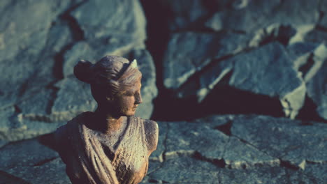 ancient statue of woman on rocky stones