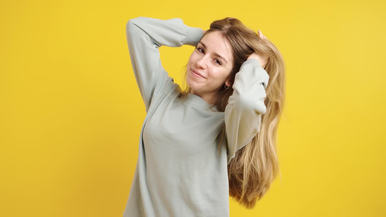 Young woman posing and smiling on yellow background