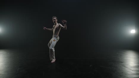 capoeira fighters performing dynamic moves on stage. martial arts, dance, and acrobatics in action. bare-chested athletes showcasing strength, flexibility, and technique under spotlights