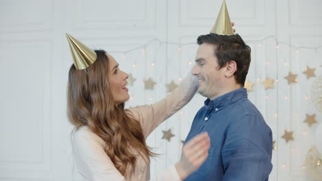 pretty woman putting golden cap on man head in modern apartment.