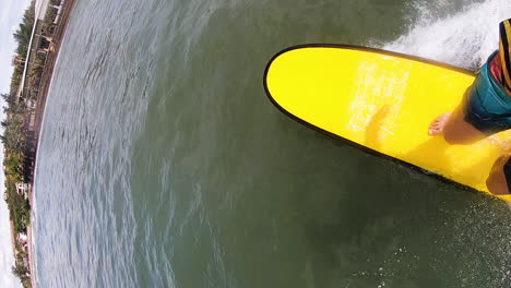 man surfing on surfboard, touching water, vertical pov slowmo