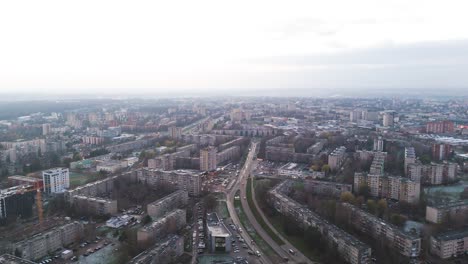 drone view of kaunas, lithuania, showcasing residential buildings, roads, and the urban sprawl extending into the distance under a cloudy sky, drone establishing shot