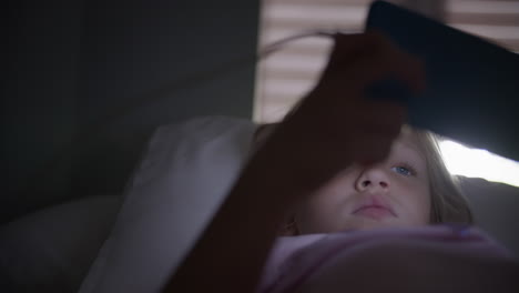una chica joven jugando al teléfono en la cama.