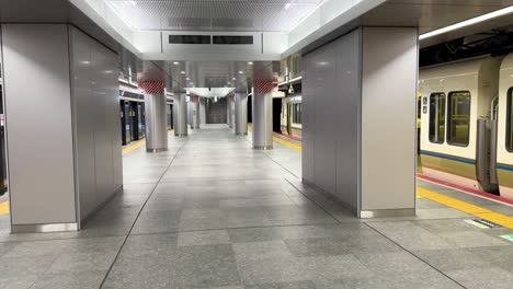 Toma-Panorámica-Que-Muestra-Trenes-Esperando-En-Una-Estación-De-Tren-Subterránea-Vacía-De-Osaka.