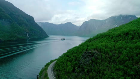 reversing dron shot of norwegian fjord with ship in distance