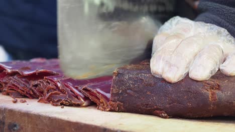 a person cutting a large piece of turkish pastirma