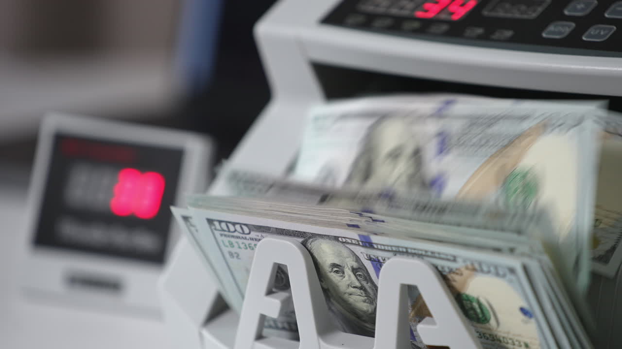 Switched on money counting machine. Hundred dollar bills turning in the counting mechanism. Close up.