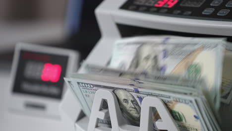 switched on money counting machine. hundred dollar bills turning in the counting mechanism. close up.