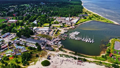 a wide aerial view captures the summer zvejnieksvētki (fisherman's festival) in the coastal town of engure, latvia, showing the harbor full of sailboats and a bustling fair