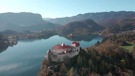 aerial view of lake bled castle flying from left to right with the stunning lake bled and lake bled island and church in the background on a autumn morning in slovenia