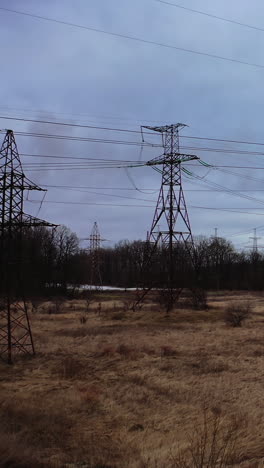 high voltage electric towers on field. transmission power lines. high voltage power line insulators. electric towers with electric cables stretched between them, wires with high voltage current. vertical video