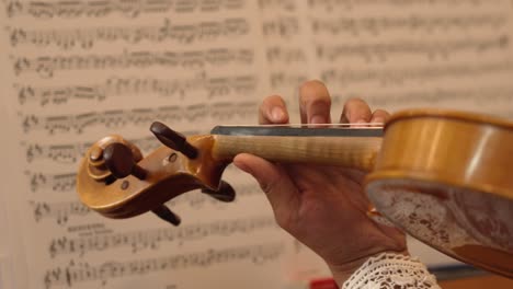Close-Up-of-a-Violin-Being-Played-with-Musical-Sheet-Notes-in-the-Background