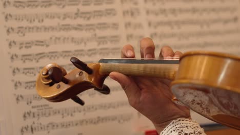 close up of a violin being played with musical sheet notes in the background