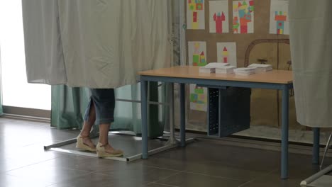 Piernas-De-Un-Votante-Dentro-De-Una-Cabina-De-Votación,-Seleccionando-Su-Voto.